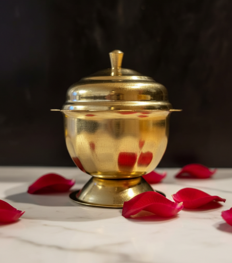 Kumkuma Bharani brass box on white marble with rose petals