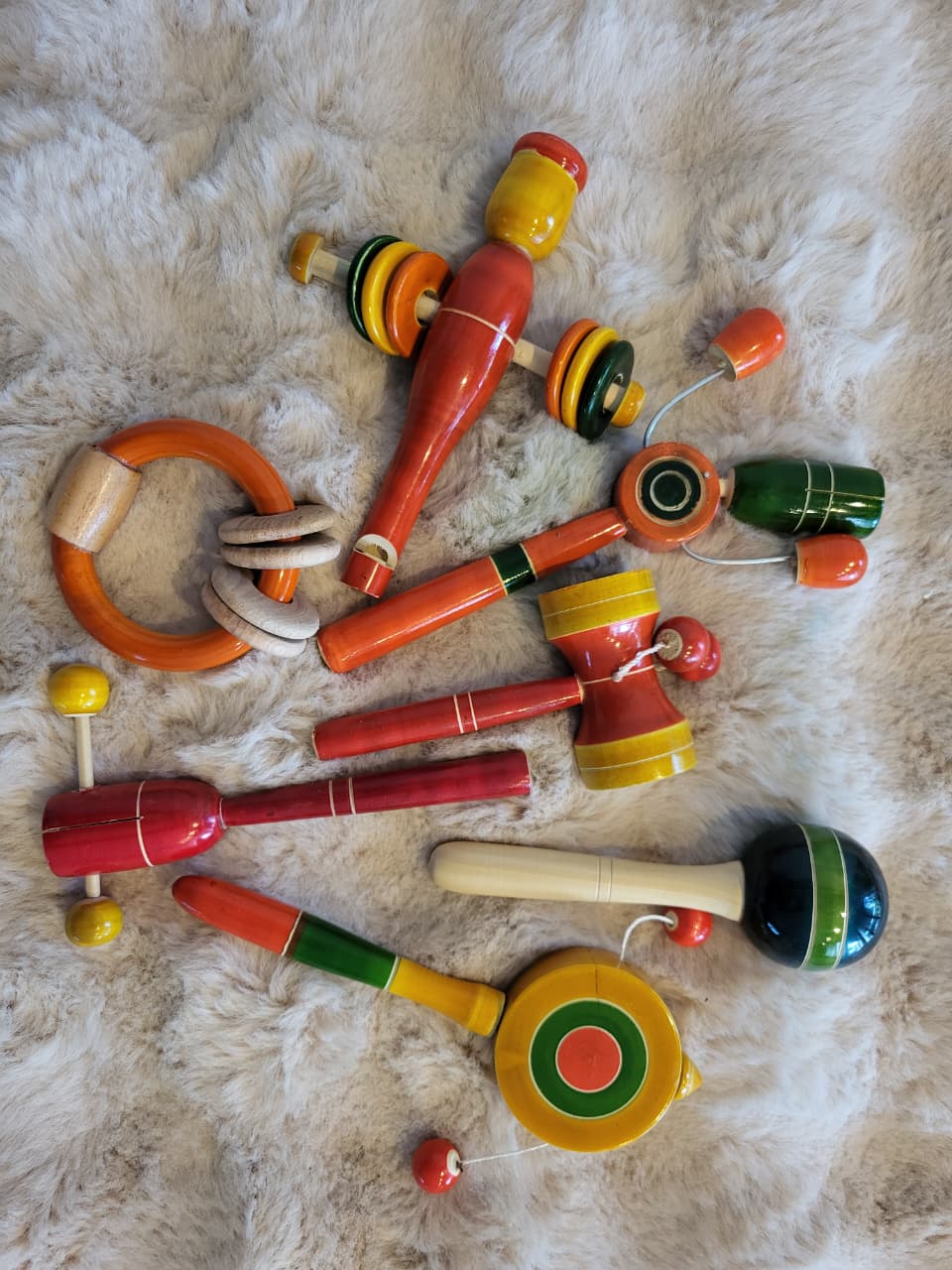 Channapatna wooden baby toy gift set flat lay showing ring rattle, dumbbell, hammer, spinning top, yo-yo, maraca and cup-and-ball