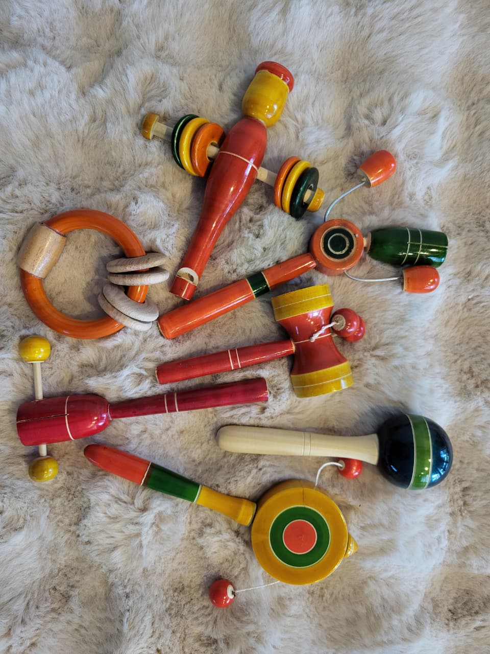 Channapatna wooden baby toy gift set on fur rug showing full assortment in vibrant lacquer colours