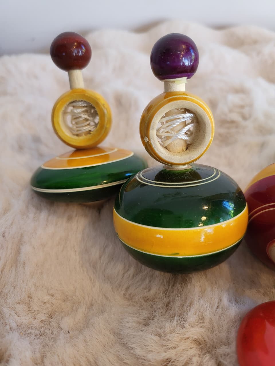 Close-up of Channapatna wooden spinning tops showing green and yellow lacquer detail and string spool