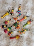 Assortment of Channapatna wooden keychain figures on white fur rug showing various designs