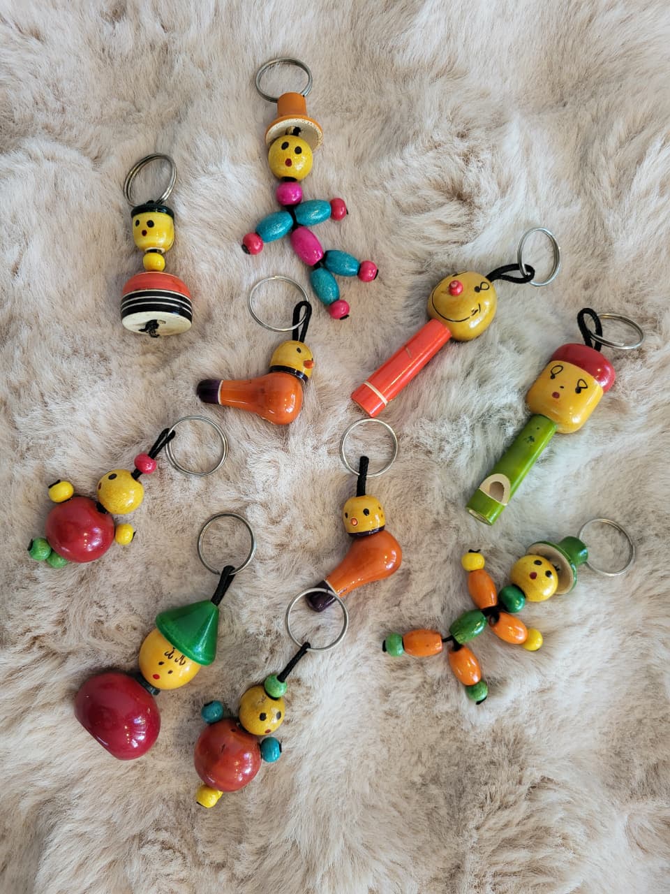 Channapatna wooden keychain figures flat lay showing whistle, bead dancer, bell and jointed characters