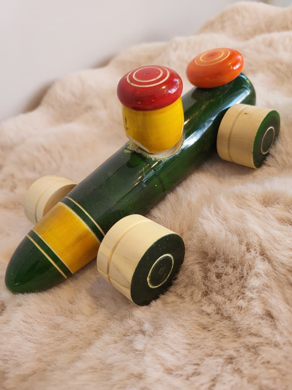 Channapatna wooden toy racing car side view with green body, yellow stripe and red mushroom cap driver