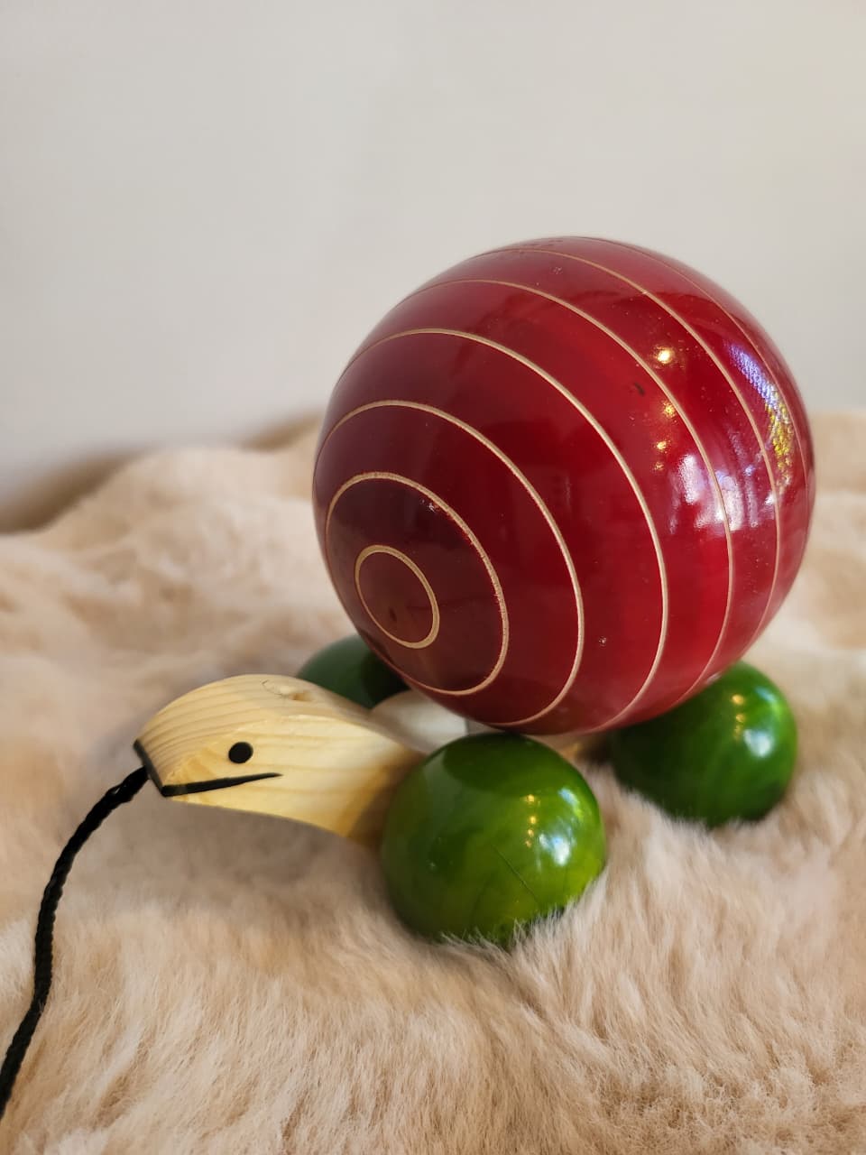 Channapatna wooden pull-along snail toy side view with red spinning ball shell and green body