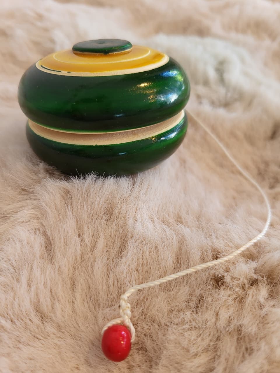Channapatna wooden yo-yo top-down view showing concentric green and yellow ring pattern