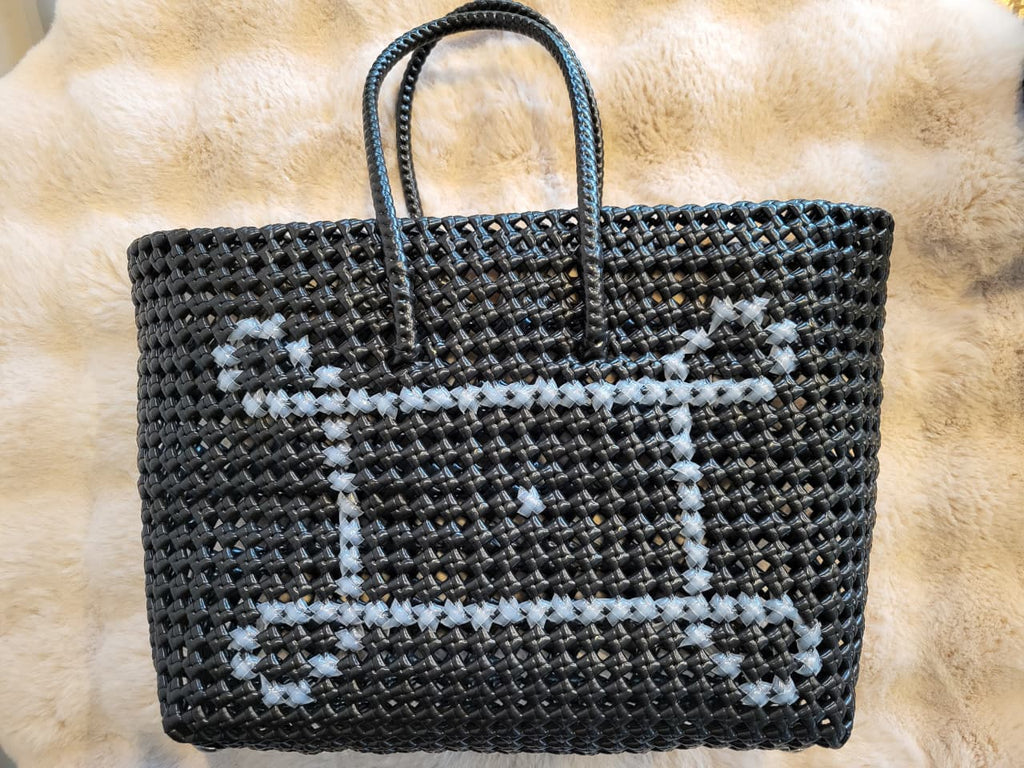 Handwoven black tote bag flat lay showing white cross-stitch pattern detail