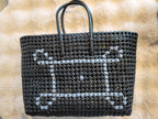 Handwoven black tote bag flat lay showing white cross-stitch pattern detail