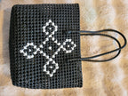 Handwoven black tote bag top-down flat lay showing white diamond cross-stitch pattern