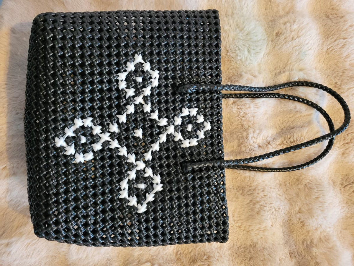 Handwoven black tote bag top-down flat lay showing white diamond cross-stitch pattern