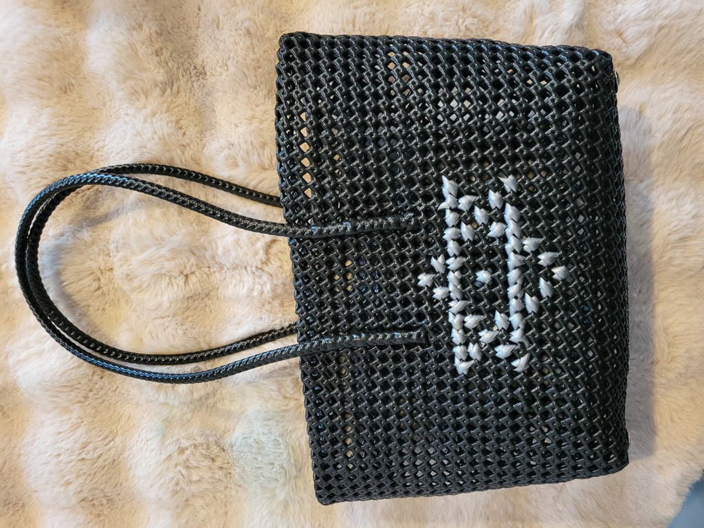 Handwoven black tote bag flat lay showing white cross-stitch heart motif detail