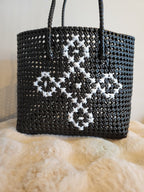 Handwoven black tote bag front view with white cross-stitch diamond motif and braided handles