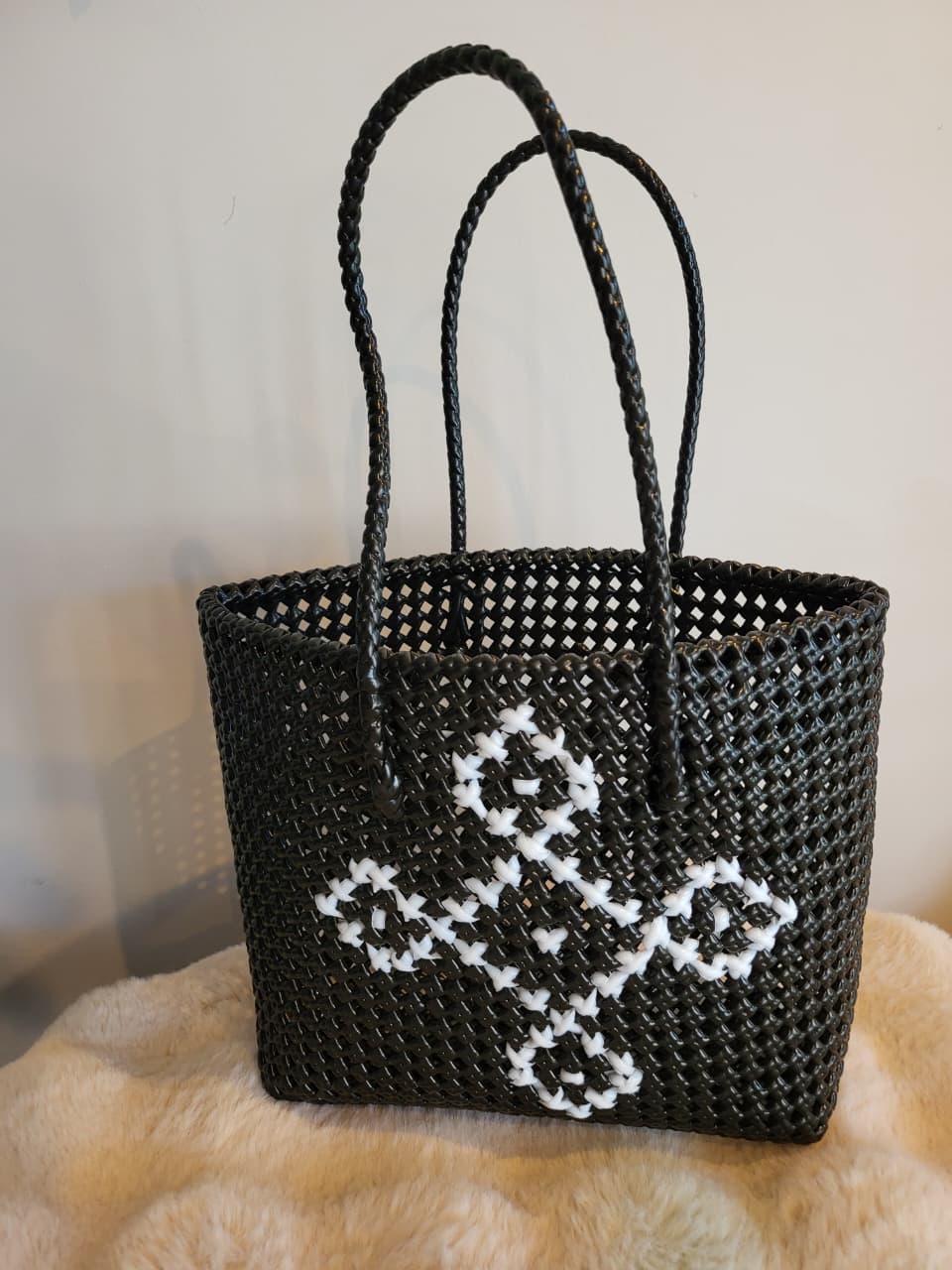 Handwoven black tote bag side angle view showing diamond motif detail