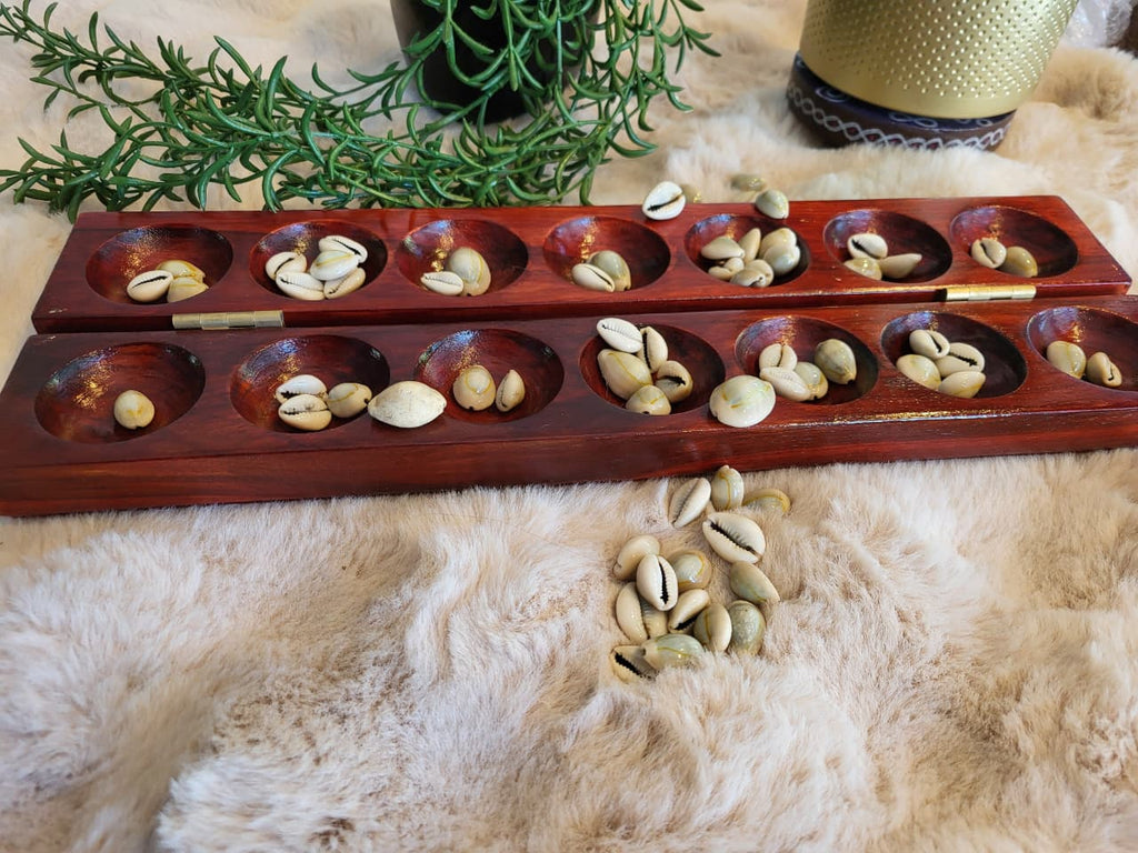 Mancala board open with cowrie shells in pits, vertical view