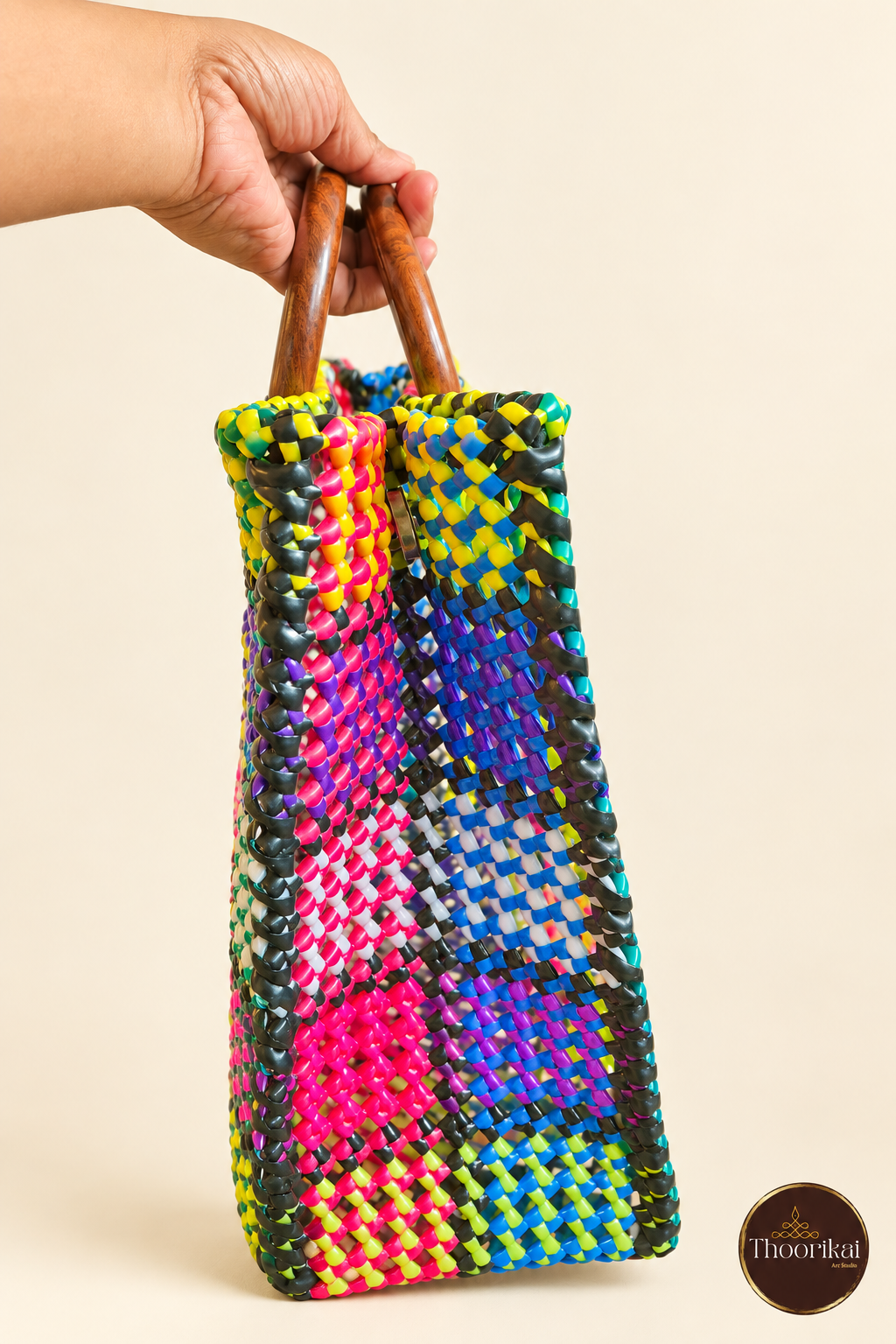 Narrow side view of multicolour Kattam market bag held by round handles
