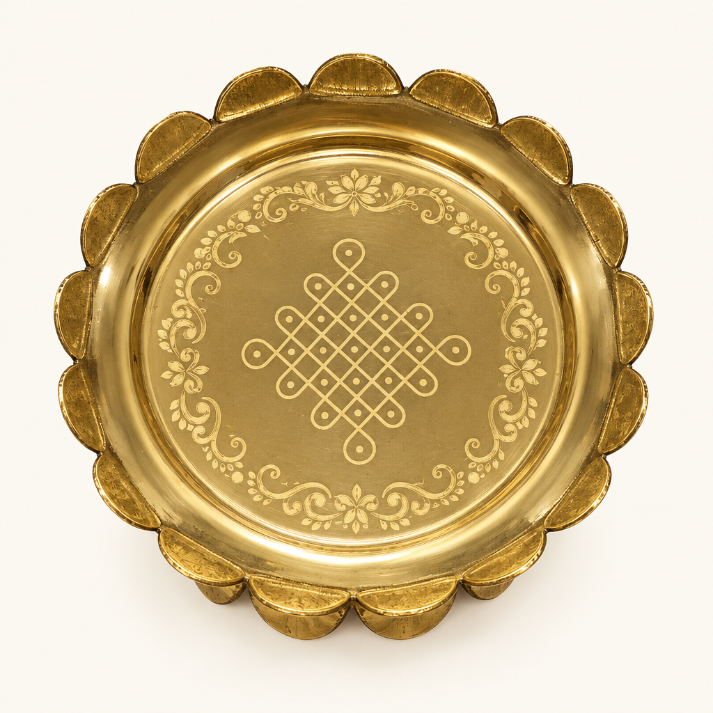 Overhead view of brass uruli with kolam engraving on ivory background