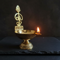 Brass Murugan Diya – moody dark background with candlelight