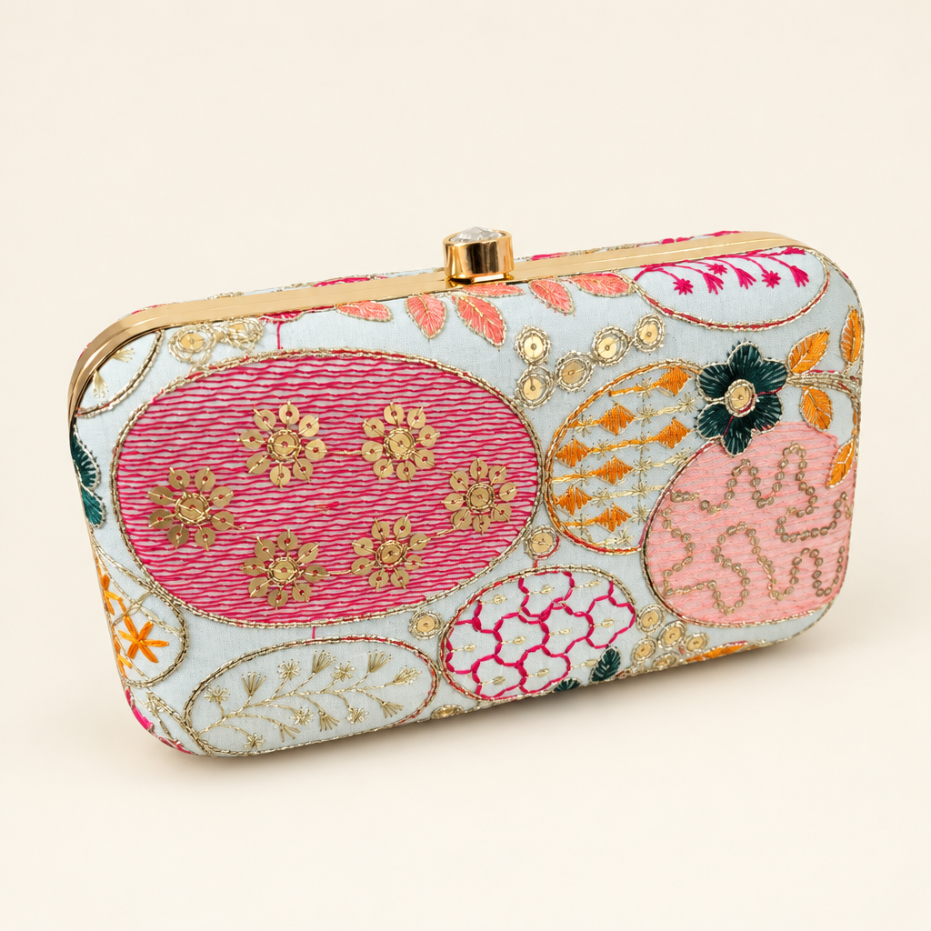 Light embroidered box clutch with pink ornamental motifs and gold-tone frame on an ivory background