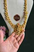 Nakshi haram pendant and hand detail against a dark green background with Thoorikai logo