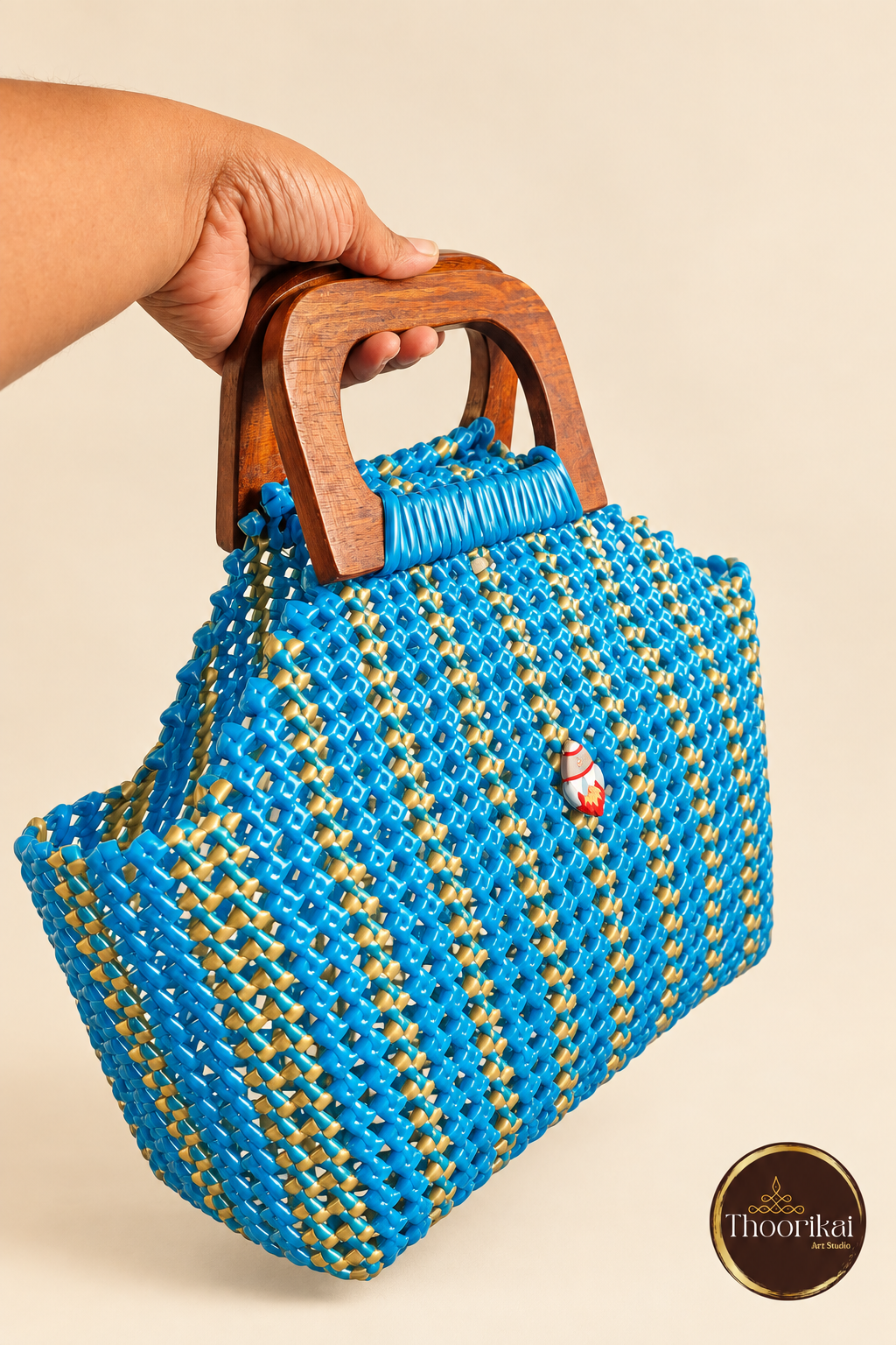 Angled hand-held view of peacock blue-gold handbag