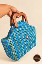 Angled hand-held view of peacock blue-gold handbag