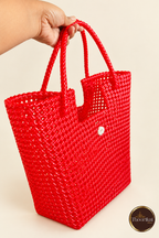Angled view of red woven tote held by its loop handles