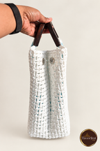 Side view of white woven handbag showing snap details