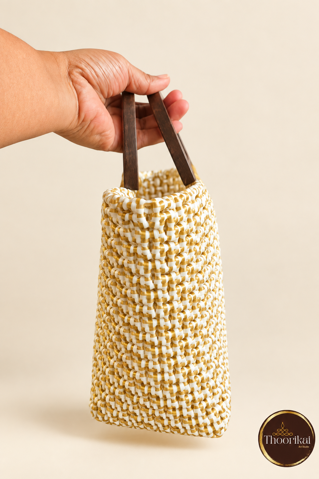 Hand-held side view of white-gold handwoven mini handbag