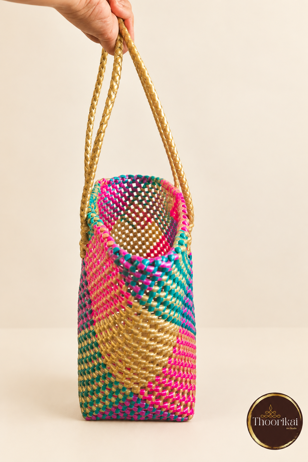 Side view of colourful woven tote held by gold-coloured handles