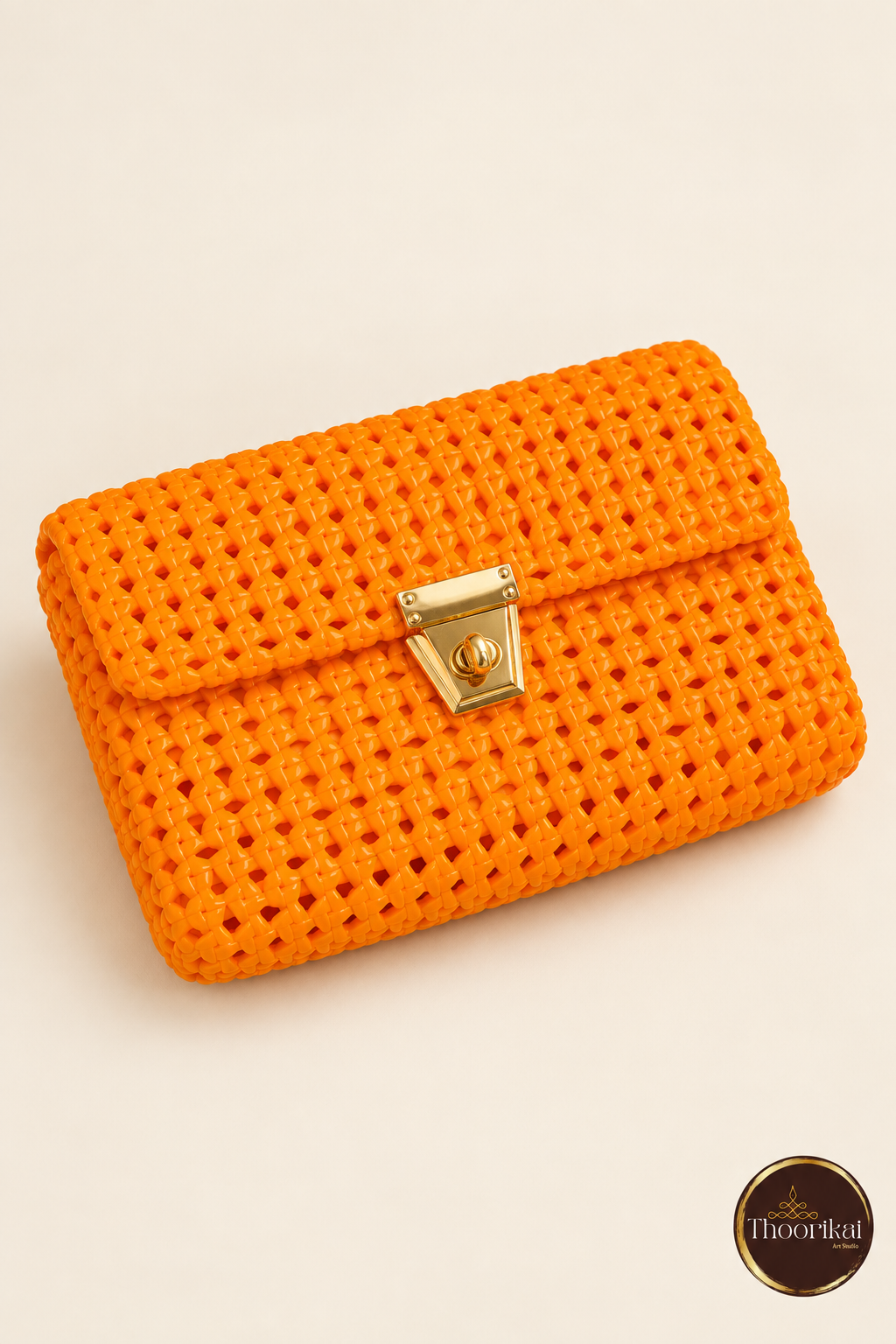 Elevated view of orange clutch showing flap weave and clasp