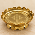 Three-quarter view of brass lotus uruli on pale stone