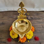 Brass Murugan Diya – overhead view with marigolds and kumkum